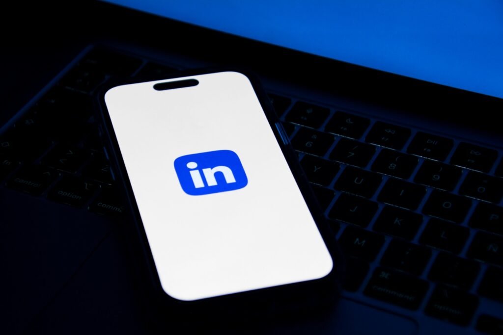 Smartphone com o ícone do LinkedIn na tela, apoiado sobre o teclado de um notebook