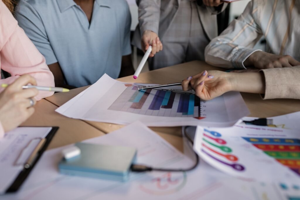 Uma equipe diversificada envolvida no planejamento e discussão de uma estratégia de negócios em torno de uma mesa de madeira interna.